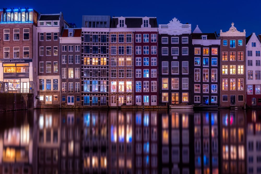 Deze grachtenpanden in Amsterdam aan het water in het donker kan je bezoeken tijdens jouw vakantie in Noord-Holland.