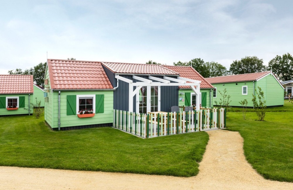Een groen gekleurd boerderijtje waarin je kan overnachten op het kindvriendelijk vakantiepark Molenwaard.